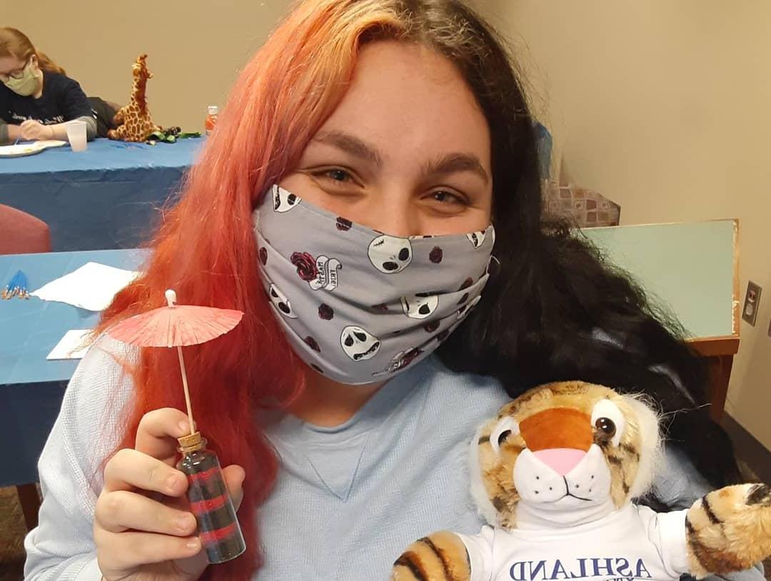Girl in a facemask holding a stuffed toy tiger